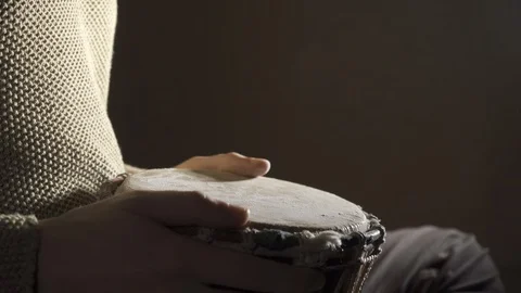 Man plays the djembe drum covered with powder, side view Stockbeeldmateriaal 114063636