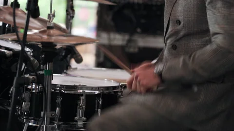 A man plays a drum kit at a party in a clipped suit Stock Footage 157385199