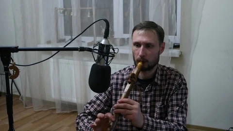 A man plays a flute in front of a microphone 스톡 동영상 102554340