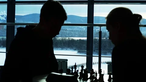 A man plays with a girl in chess at the table, backlight Stock Footage 85352759
