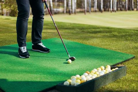 Man plays golf standing on artificial grass in sunny park Stock Photos