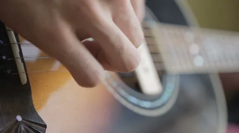 A man plays the guitar close up while sitting at a window in the apartment Vídeo Stock 64899012