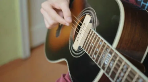 A man plays the guitar close up while sitting at a window in the apartment Stockbeeldmateriaal 64903330