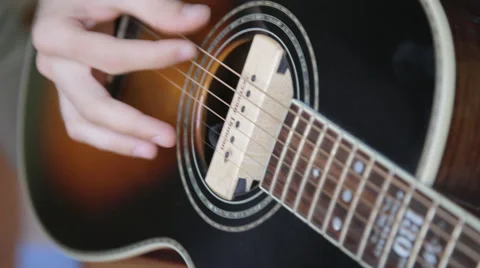 A man plays the guitar close up while sitting at a window in the apartment Stock Footage 64903726