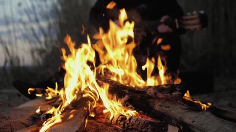 A man plays the guitar. In the foreground is a fire. Summer evening. Slow motion Stock Footage 130730213