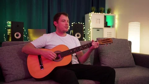 A man plays guitar sitting on the couch Stock Footage 129101356