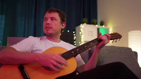 A man plays guitar sitting on the couch Stock Footage 129101404