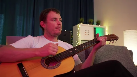 A man plays guitar sitting on the couch Stock Footage 129101414