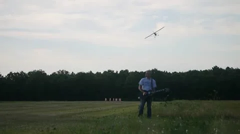 MAN PLAYS GUITAR WHILE PLANE FLIES OVER HIS HEAD Stock Footage 12110860