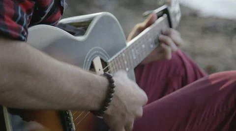 A man plays the guitar while sitting by the sea. Close up Stock Footage 64901796