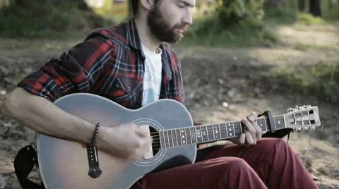 A man plays the guitar while sitting by the sea 動画素材 65221356