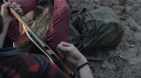 A man plays the guitar while sitting by the sea Vídeo Stock 65221390