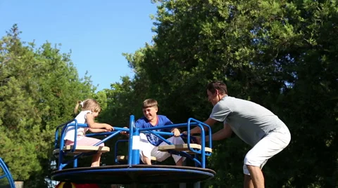 Man plays with his children on the carousel Stock Footage 52823301