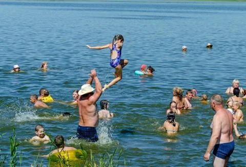 A man plays with his daughter on a pond, throwing her up above the water Stock Photos