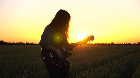 Man plays on musical instrument at meadow. Hipster playing on guitar at field Stock Footage 297253953