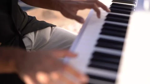 Man plays the piano while sitting on a chair on a pier by the sea Stock Footage 219661747