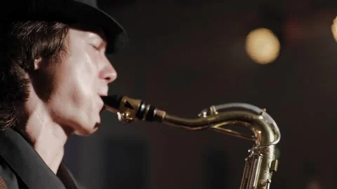 Man plays saxophone. Side view close-up of face of man in hat playing saxophone Stock-Footage 248214616