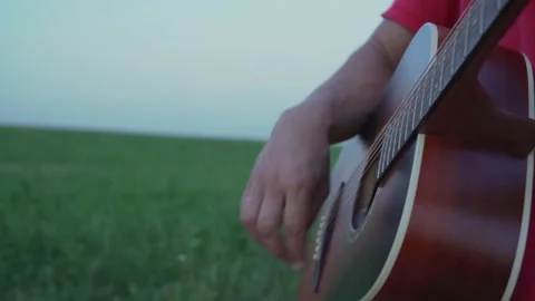 Man plays on strings of acoustic guitar during day Stock Footage 159100829