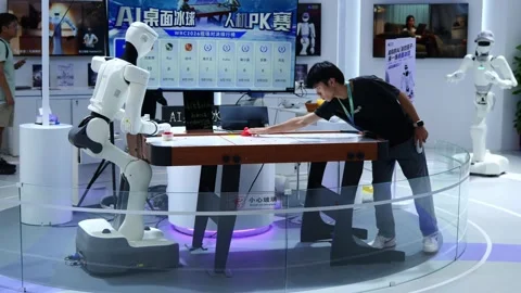 A man plays table hockey with a robotic arm at a tech expo. Stock Footage 344272985