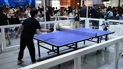A man plays table tennis with a humanoid robot at an expo. 库存影片 344272502