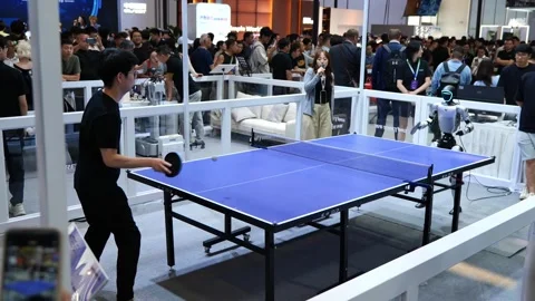 A man plays table tennis with a humanoid robot at an expo. Vídeo Stock 344272754