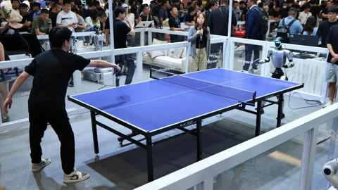 A man plays table tennis with a humanoid robot at an expo. Vídeo Stock 344272812