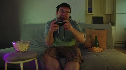 A man plays video game puts down the gamepad, screams, raises his hands up Stock Footage 314395991