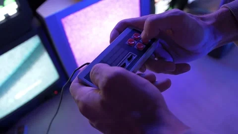 Man plays video games the console on the background of old TVs in the led room Stock Footage 160254437