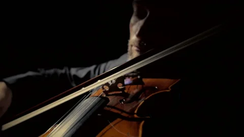 A man plays the violin in a dark room. Black background. Close up Stock Footage 116877366