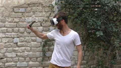 A man plays virtual augmented reality game using head mounted display, sword Stock Photos