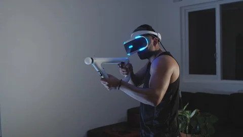 Man Plays Virtual Reality Video Game with Gun and Goggles in Living Room, Night Stock Footage 108880602