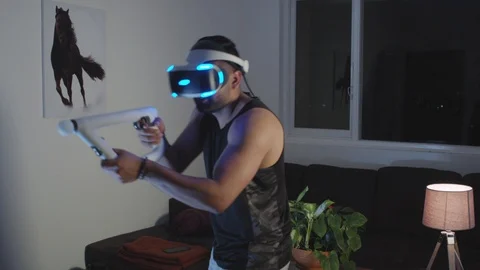 Man Plays Virtual Reality Video Game with Gun and Goggles in Living Room, Night Stock Footage 108881142