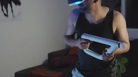 Man Plays Virtual Reality Video Game with Gun and Goggles in Living Room, Night Stock Footage 108881242