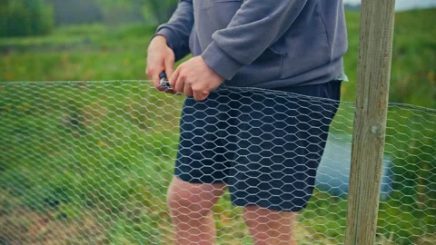 A Man With A Plier Tool Installing A Wire Mesh Fence. Close-up Shot Stock Footage 313986197