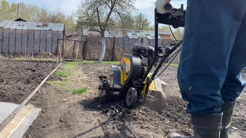 Man plows the land with a mini combine harvester for growing vegetables Stock Footage 240728622