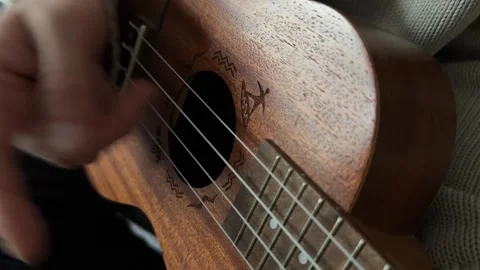 Man plucking ukulele strings close up at home, playing melody, music practice Stock Footage 337105329