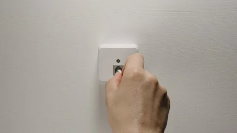 Man Plugging And Unplugging The Internet Cord Into Wall Socket On A White Wall Stock Footage 110774655