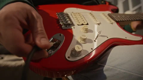 Man Plugging Audio Cable into Red Electric Guitar in Studio Stock Footage 337498844