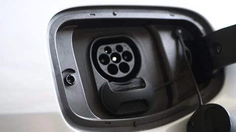 A man is plugging in a charger to charge an electric car battery at home. Stock Footage 322622759