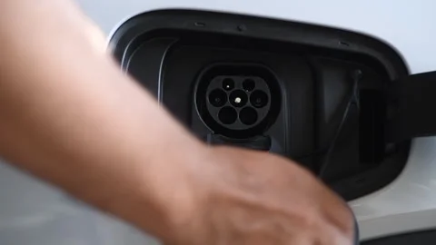 A man is plugging in a charger to charge an electric car battery at home. Stock-Footage 322622934