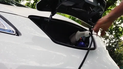 Man plugging a charging cable into an electric car Stock Footage 79501423