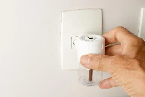 Man Plugging in An Electric Plug in Mosquito Repeller Foto stock