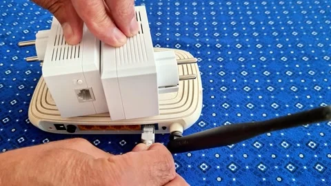 Man Plugging Ethernet Cable into Wi Fi Router with Powerline Adapters Stock Footage 341840592