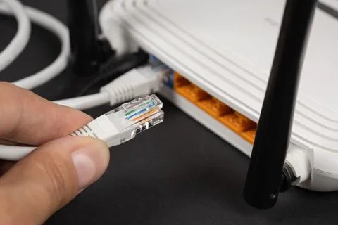Man plugging internet cable into wi-fi router Foto stock