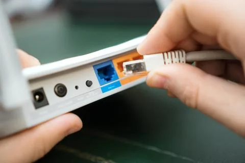 Man plugging internet cable into wifi router. Stock Photos