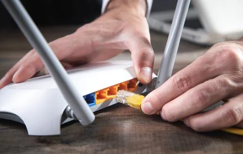 Man plugging internet cable into wifi router. Foto stock