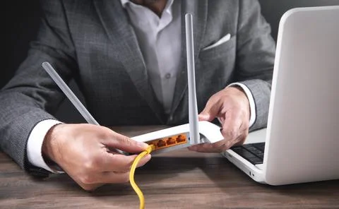 Man plugging internet cable into wifi router. Stock Photos