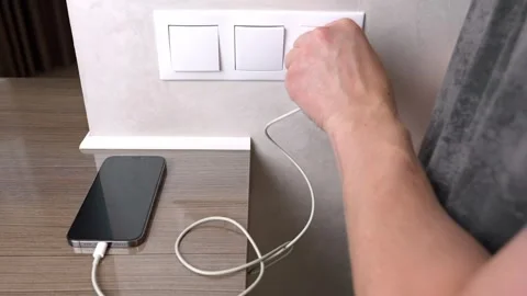 Man plugging a smartphone charger into a wall socket Stock Footage 317687424