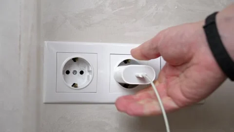 Man plugging a white charger into a white wall socket Stock Footage 317687092