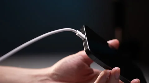 Man plugging white charging cable into smartphone and unplugging it, repeating Stock Footage 297623205